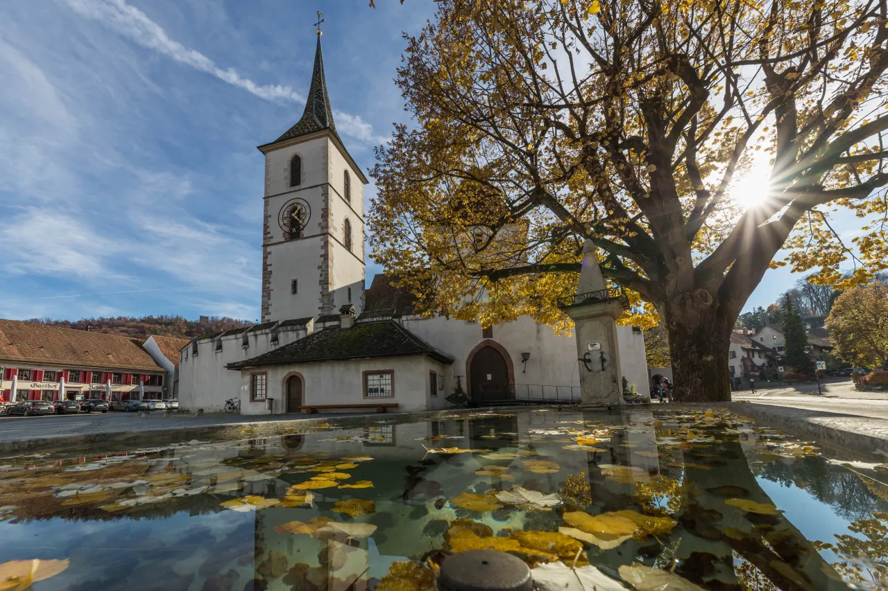 Herbstsonne auf dem Kirchplatz: Dorfkirche mit Dorfbrunnen Herbst (Foto: Peter Wehrli)