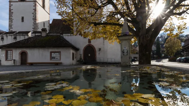 Bl&auml;tter im Dorfbrunnen &mdash; Dorfkirche mit Dorfbrunnen Herbst (Foto: Peter Wehrli)